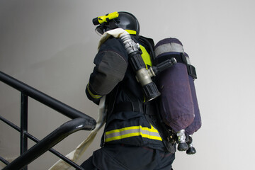 Fototapeta premium close-up, a firefighter, having laid a line for water supply, is waiting for a command to extinguish from a trunk, being in the building on the stairs
