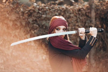 Outdoor portrait of young female in pirate costume swinging a sword.