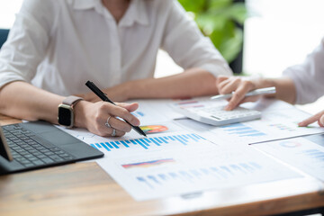 Close up view two business woman investment advisors pointing at graph and analyzing financial report in meeting.