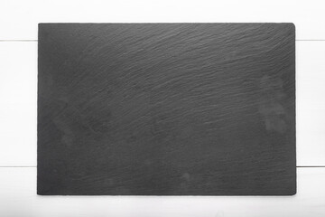 Slate board on wooden background. Cutting board. Space for text.