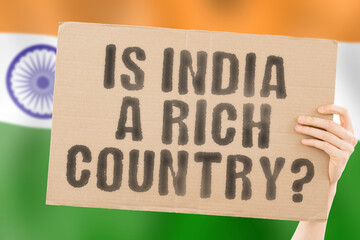 The question " Is India a rich country? " on a banner in men's hand. Money. Finance. Currency. Rate. Economy. Wealth. Salary. GDP. Million. Inequality. Economic. Income