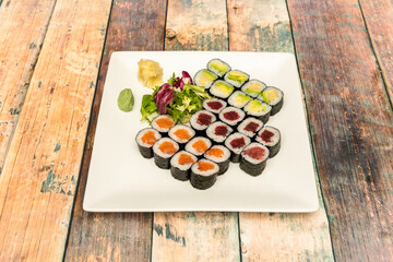 Fototapeta na wymiar Assorted sushi maki of red tuna, ripe avocado, Norwegian salmon, white rice with Japanese vinegar, wasabi, ginseng and nori seaweed