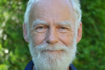 Portrait of a happy smiling elderly gray-haired man with a gray beard and mustache close-up