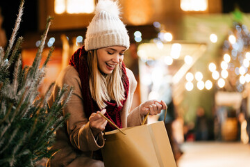 Happy young beautiful woman choosing christmas present and tree at market