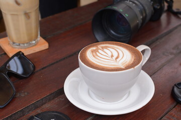 Top view of hot latte with camera and glasses on side. Work in a coffee shop. cappuccino with latte art: Pasuruan, Indonesia - August 28, 2020