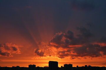 bright orange sunset over the city and the rays of the sun through the clouds