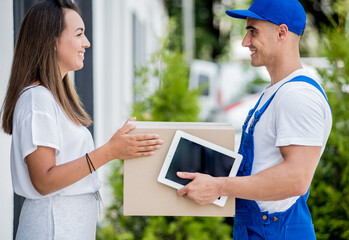 Young courier delivering goods to a young woman at home