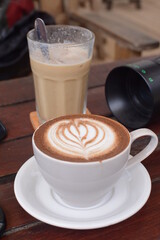 coffee latte art in the shop cafe. A new morning with coffee to eat to increase the workforce. Cup of cappuccino with art on wooden table. Latte art coffee in white cup with saucer on wooden table