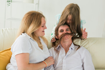 Family sitting on sofa in their living room. Daughter have injury hand but she is happy be together her family.