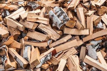 Preparation of firewood for the winter. Stacks of firewood in the forest. Firewood background. Sawed and chopped trees. Stacked wooden logs. Closeup view of cut and split firewood stacked outdoor