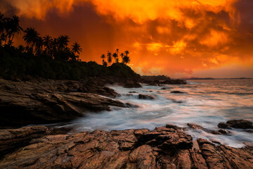 Obraz premium Sunset on the rocky shore of tropical sea