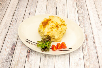 pancake stuffed with salmon and potato topped with melted cheese gratin, cherry tomatoes and lettuce with a touch of balsamic vinegar