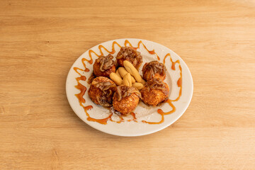 Delicious goat cheese croquettes with caramelized onion and peaks of country bread on wooden table