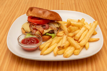 Beef burger with fried bacon, melted cheese, roasted onion, tomato slices and lettuce with brioche bread, ketchup and a side of homemade chips