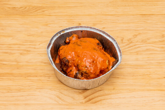 Whole Charcoal-roasted Chicken With Mojo Picon Sauce On Top In Aluminum Takeaway Container