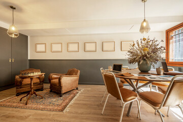 meeting and recreation room with work table and vintage armchairs upholstered in brown leather with a chess game in progress