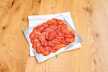 Portion of Iberian loin cut into thin slices on aluminum foil for takeaway