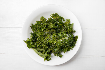 Heap of oven baked crunchy curly kale chips in bowl also known as  leaf cabbage. Healthy tasty...