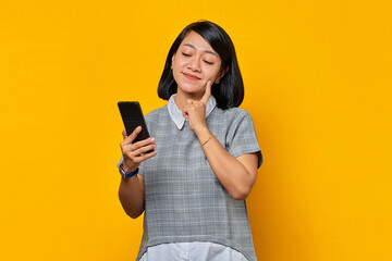 Naklejka premium Portrait of smiling young Asian woman thinking about question with finger hand on chin and holding mobile phone