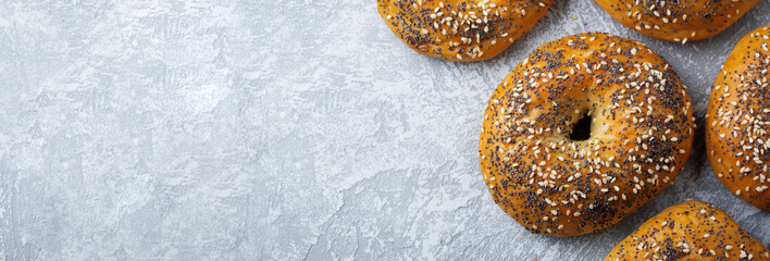 Variety fresh whole-grain bagels with poppy seeds, sesame seeds on a light concrete or stone...