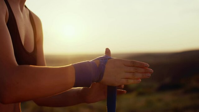 Woman in nature a sports uniform wraps her hand with blue bandages, a closeup hands. Woman wraps hands with bandages. Concept of martial arts