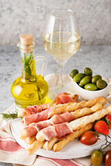 Traditional Italian snacks for wine, breadsticks (grissini), tomatoes, prosciutto (jamon), strawberries and olives.