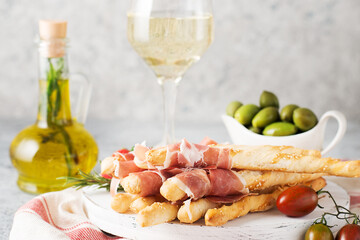 Traditional Italian snacks for wine, breadsticks (grissini), tomatoes, prosciutto (jamon), strawberries and olives.