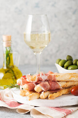 Traditional Italian snacks for wine, breadsticks (grissini), tomatoes, prosciutto (jamon), strawberries and olives.