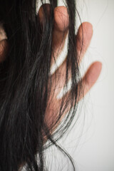 Mano y partes de la piel de una mujer junto con su pelo negro y lunares.