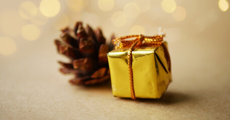 Christmas gift banner. Golden wrapped box and pine cone. Blurry glowing 