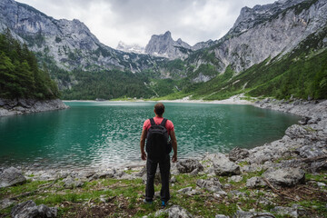 Fototapeta na wymiar Man traveler enjoying view of Dachstein peak mountains on a Upper Gosau Lake. Gosau, Salzkammergut, Austria, Europe