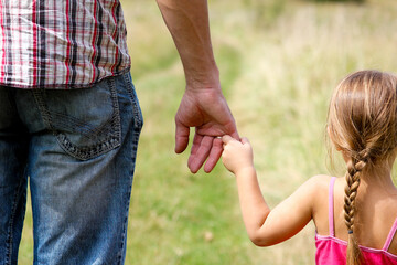 the parent holds the hand of a small child