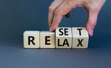 Relax and reset symbol. Businessman turns cubes and changes the word 'relax' to 'reset'. Beautiful grey table, grey background. Business, relax and reset concept. Copy space. - obrazy, fototapety, plakaty