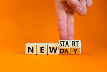 New day and start symbol. Businessman turns wooden cubes and changes words 'new day' to 'new start'. Beautiful orange table, orange background. Copy space. Business, new day and start concept.