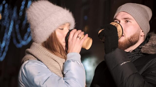 Young couple in the city during christmas drink hot coffee