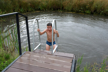 Fototapeta na wymiar Kid climbs stairs from pond