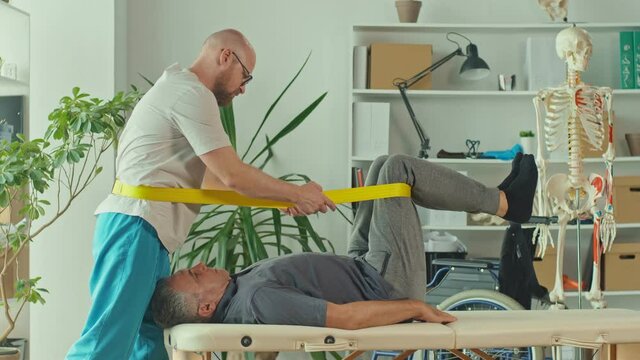 The Doctor Conducts a Physiotherapy Session with an Older Man With a Brain Stroke at the Modern Rehabilitation Clinic. The Affected Nervous System, Paralysis. Health Care Concept.