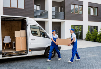 Two removal company workers are loading boxes into a minibus.