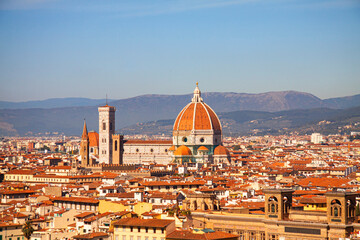 Fototapeta na wymiar Santa Maria del Fiore cathedral in Florence, Italy. Aereal panoramic view with dome by Filippo Brunelleschi, and bell tower dominating the skyline in Tuscany, Italy. Mountains and blue sky background.