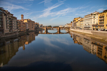 Obraz premium Beautiful view down the river Arno with Ponte Alle Grazie in Florence, Italy and italien houses of both sides reflecting in the water and blue sky background.