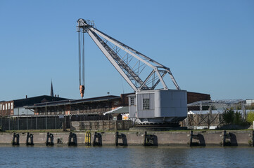 Historical harbor crane from 1893 at the docks in the city port of Luebeck on the river Trave, blue...