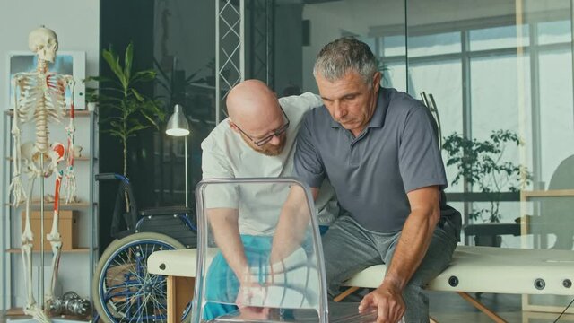 A Sick Man With a Brain Stroke Undergoes a Rehabilitation Program with a Physiotherapist in a Modern Clinic. Incapacity for Work, Limited Movement, Paralysis. Elderly Health Support Concept.