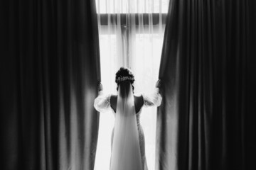 silhouette of bride  looking outside the  window in black and white picture