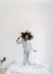 Young afro american woman jumping on bed