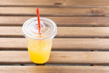 A view of a plastic drinking cup on a wood table surface.