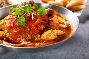 A view of a tray of cooked Dungeness crab, with a spicy red broth.