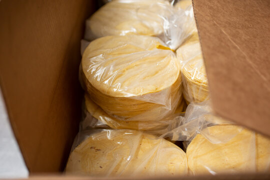 A view inside a large cardboard box, full of packages of freshly made corn tortillas.