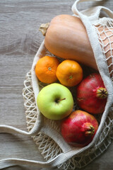 Crochet bag filled with butternut squash, pomegranates, apples and tangeriens. Top view.