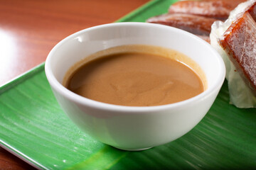 A closeup view of a condiment cup of peanut dipping sauce. This goes with spring rolls.