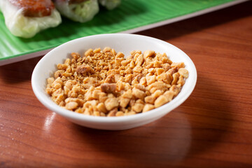 A closeup view of a saucer of crushed peanuts, a topping used for spring rolls.